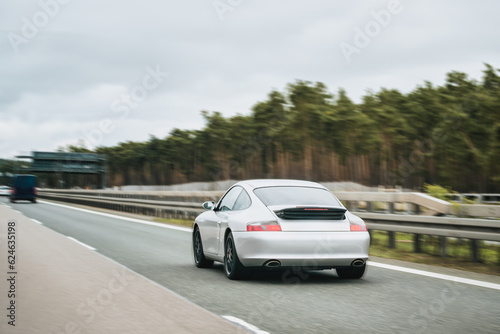Exquisite Speed and Style on the Highway. Modern European Sportcar. Silver German roadster vehicle on the highway. Silver sport coupe. The expensive sports car on public roads. Autobahn speeding