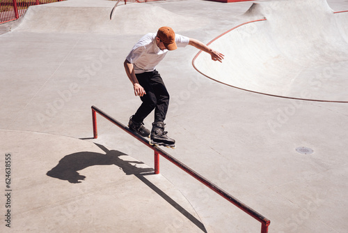 aggressive roller skater performing a trick on a railing in skatepark