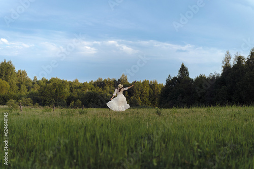 A woman in a white dress and hat runs through a flowering field. photo