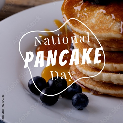 Enjoy national pancake day text in white over pancake stack on plate with blueberries and syrup