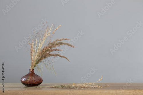 dried wild cereals in glass vase on background dark wall