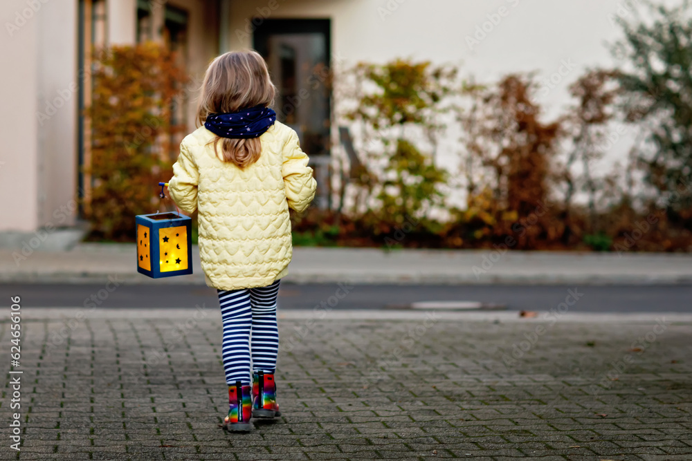 Little preschool kid girl holding selfmade traditional lanterns with