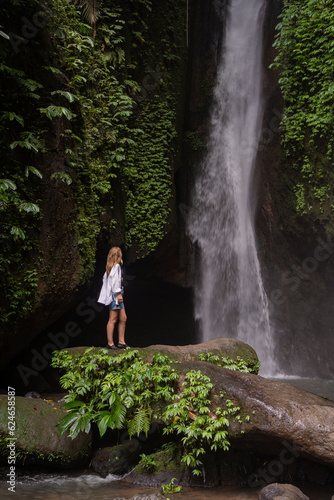 A woman standing in front of waterfall in the jungle. Travel Indonesia. Hidden beauty of the island