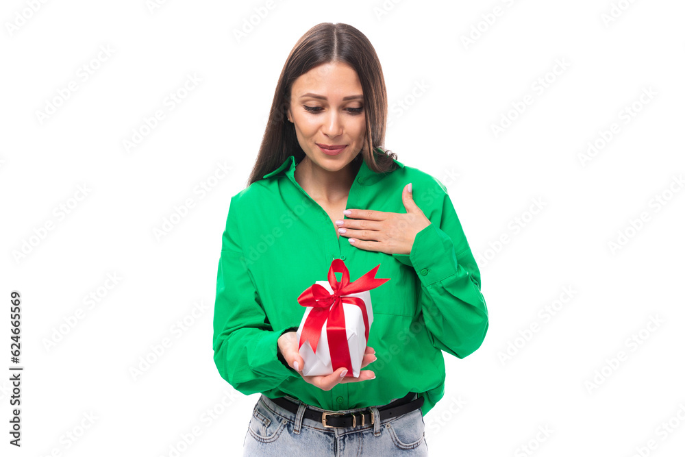 Fototapeta premium joyful well-groomed brunette long-haired young woman in a green shirt received a gift for her birthday on a white background with copy space