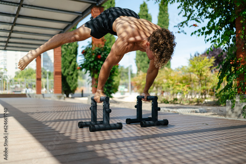 Strong young sportsman doing calisthenics photo