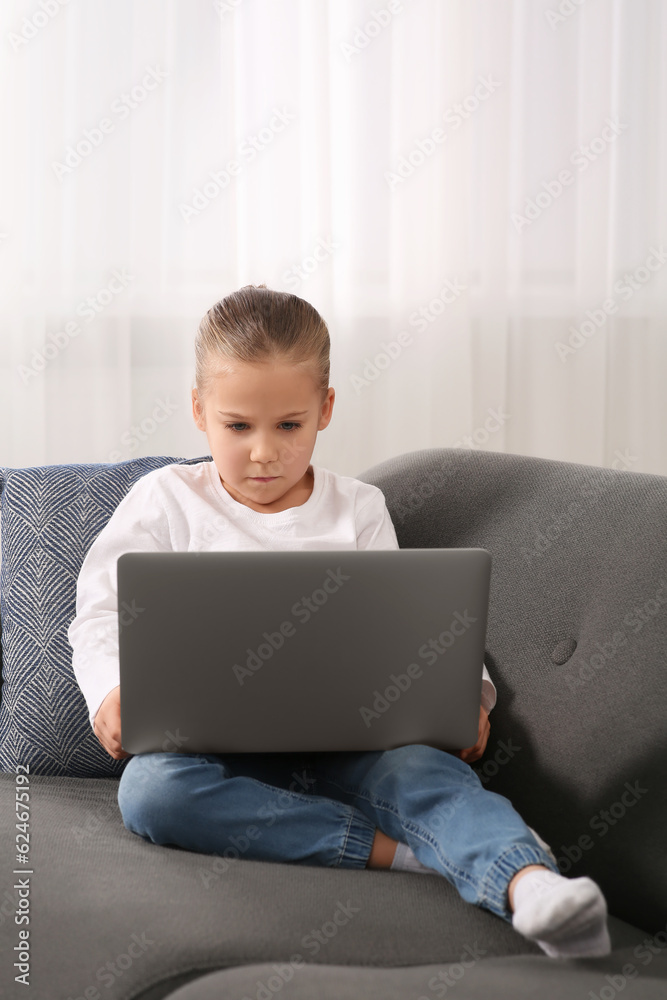 Little girl using laptop on sofa at home. Internet addiction Little girl using laptop on sofa at home. Internet addiction