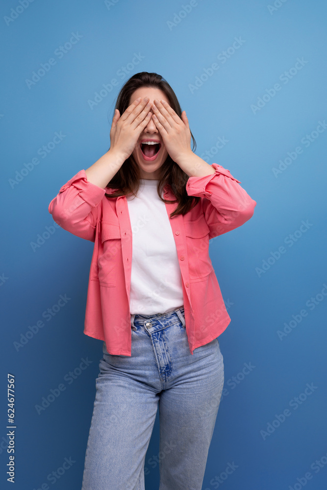 smiling brunette woman with hair below her shoulders in a shirt closed her hands in anticipation of a surprise smiling brunette woman with hair below her shoulders in a shirt closed her hands in anticipation of a surprise