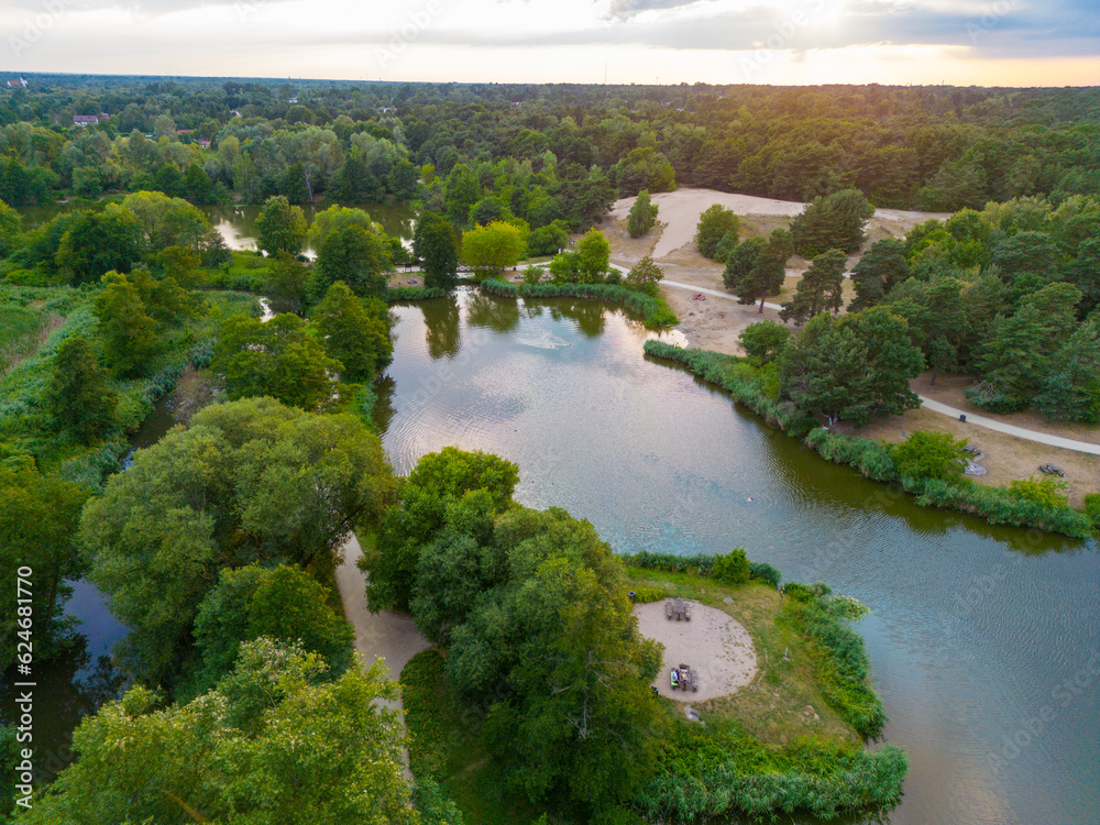 Lake with a sand beach surrounded with trees in Poland seen from above