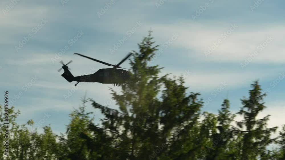 4K video with a military helicopter flying at high speed over a road next to a forest with soldiers inside it. Military aviation concept video. 4K video with a military helicopter flying at high speed over a road next to a forest with soldiers inside it. Military aviation concept video.