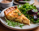 Quiche Lorraine on a white plate, surrounded by pieces of bread and green salad