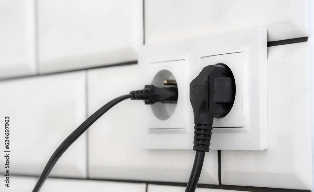 Electrical cable plug in wall socket, energy saving concept. Wire plastic equipment with voltage closeup macro Electrical cable plug in wall socket, energy saving concept. Wire plastic equipment with voltage closeup macro