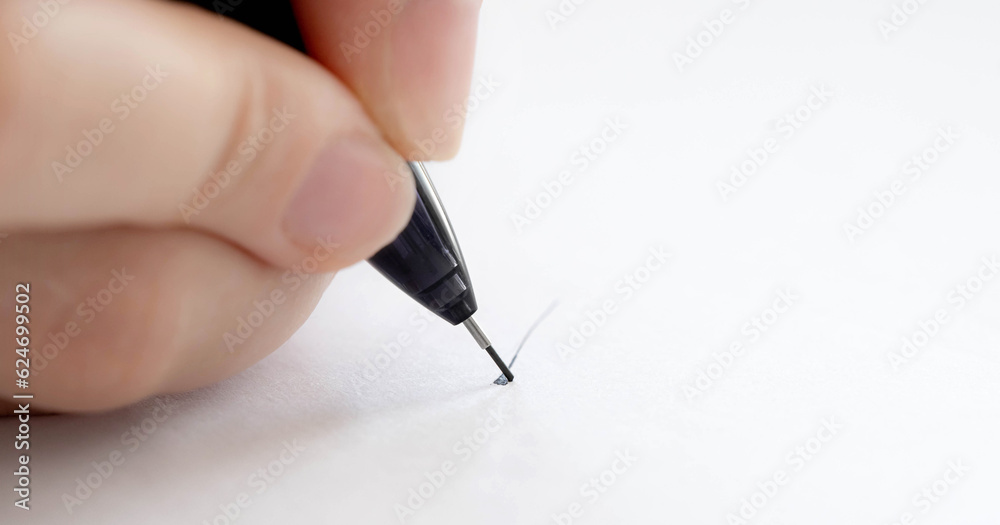Person hand holding pen and writing on white paper closeup. Fingers with pencil drawing on blank macro view Person hand holding pen and writing on white paper closeup. Fingers with pencil drawing on blank macro view