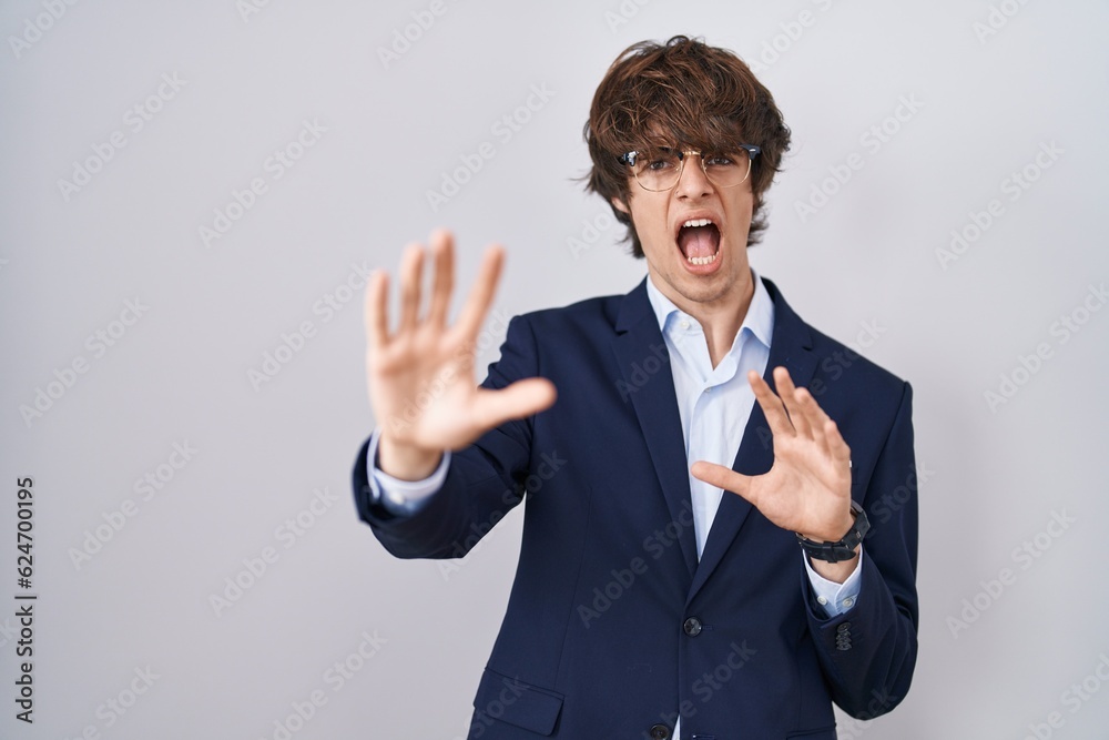 Hispanic business young man wearing glasses afraid and terrified with fear expression stop gesture with hands, shouting in shock. panic concept. Hispanic business young man wearing glasses afraid and terrified with fear expression stop gesture with hands, shouting in shock. panic concept.