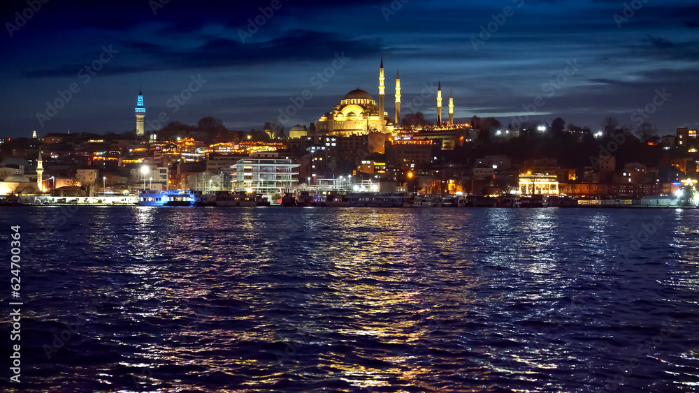 Istanbul, Turkey - February 2023: calm sea waves in Bosphorus reflecting Ayasofya Mosque and illuminated seaside restaurants