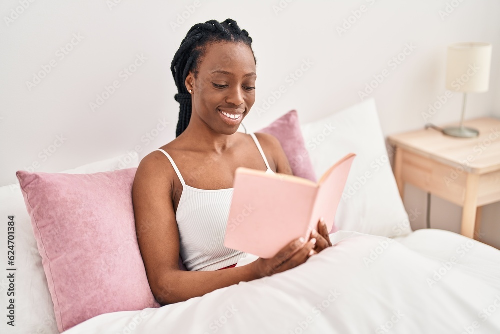 African american woman reading book sitting on bed at bedroom African american woman reading book sitting on bed at bedroom