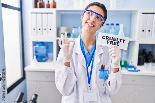 Young beautiful woman working on cruelty free laboratory doing ok sign with fingers  smiling friendly gesturing excellent symbol