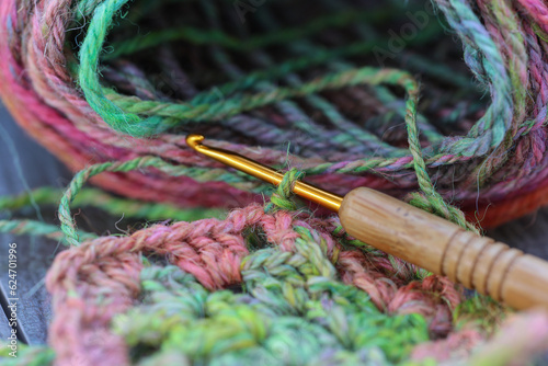 Closeup detail of crochet work with a colourful skein of organic natural handspun and handdyed merino sheep wool, silk, linnen mix yarn fleece, spun on a traditional spinning wheel	 photo