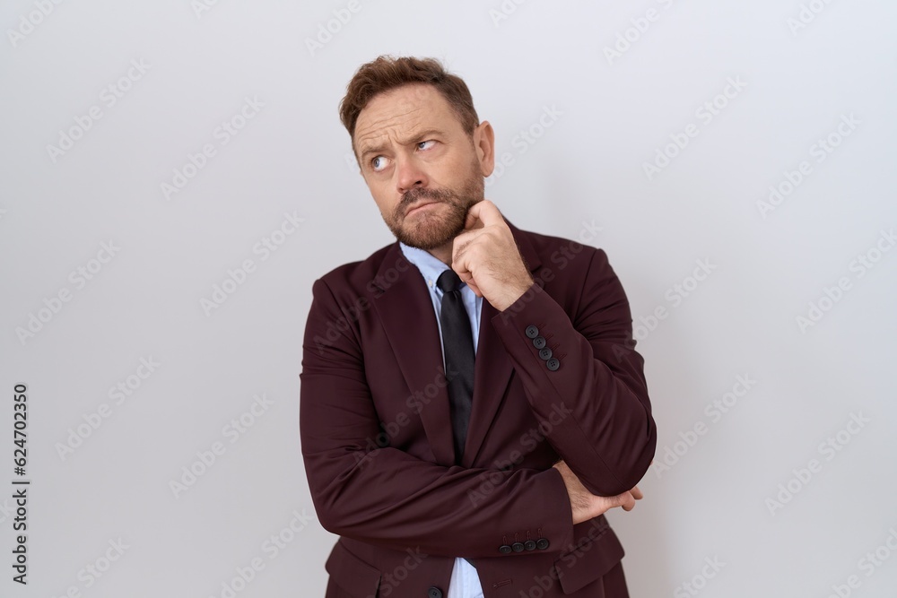 Middle age business man with beard wearing suit and tie with hand on chin thinking about question, pensive expression. smiling with thoughtful face. doubt concept. Middle age business man with beard wearing suit and tie with hand on chin thinking about question, pensive expression. smiling with thoughtful face. doubt concept.
