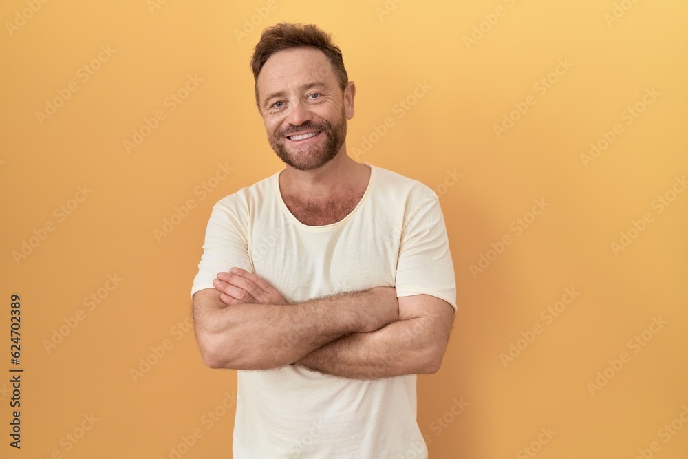 Middle age man with beard standing over yellow background happy face smiling with crossed arms looking at the camera. positive person. Middle age man with beard standing over yellow background happy face smiling with crossed arms looking at the camera. positive person.