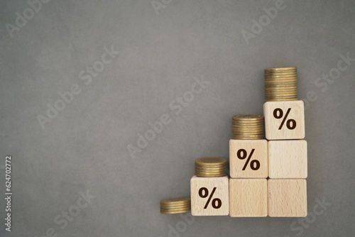 Wooden cube blocks with percentage sign and stack of coins. For financial and business growth interest rates and mortgage rates interest on investment inflation concept on grunge grey background