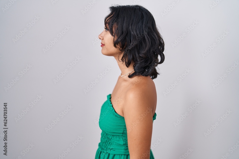 Fototapeta premium Young hispanic woman standing over isolated background looking to side, relax profile pose with natural face and confident smile.