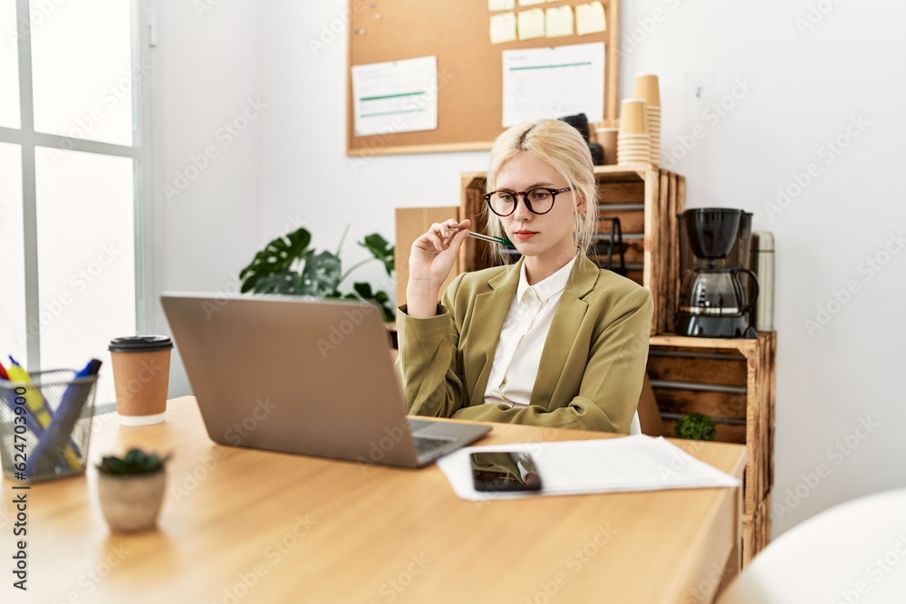 Young blonde woman business worker using laptop thinking at office