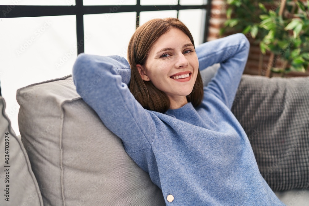 Young blonde woman relaxed with hands on head sitting on sofa at home Young blonde woman relaxed with hands on head sitting on sofa at home