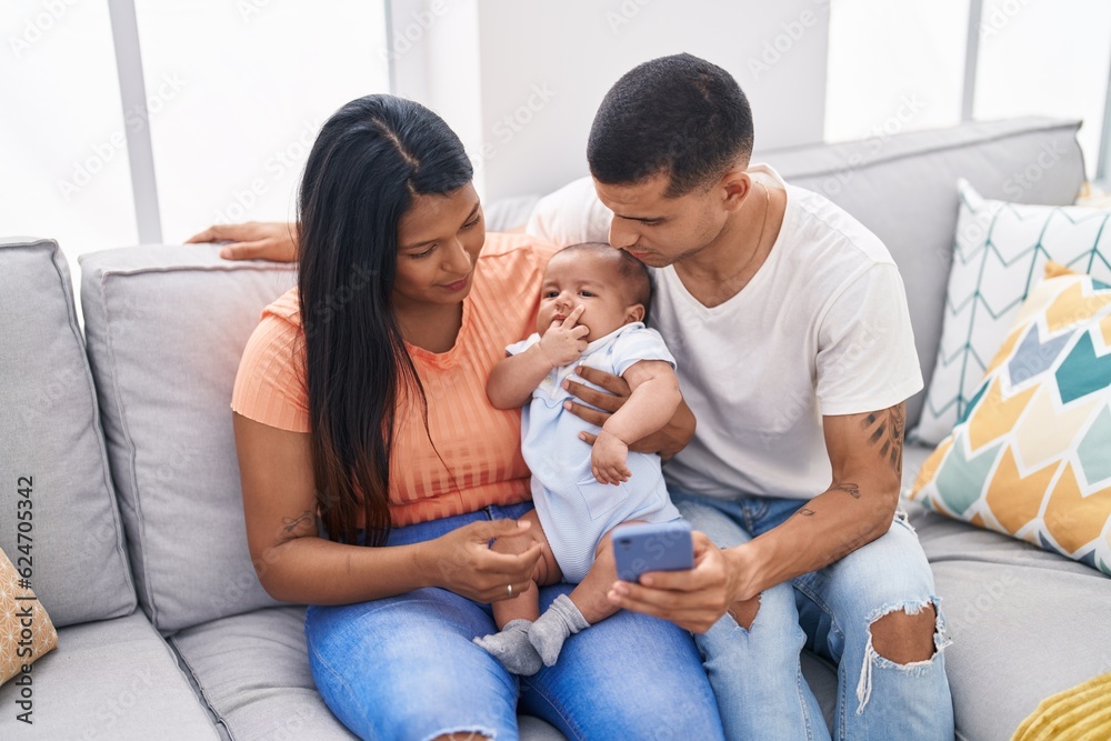 Hispanic family using smartphone sitting on sofa at home Hispanic family using smartphone sitting on sofa at home