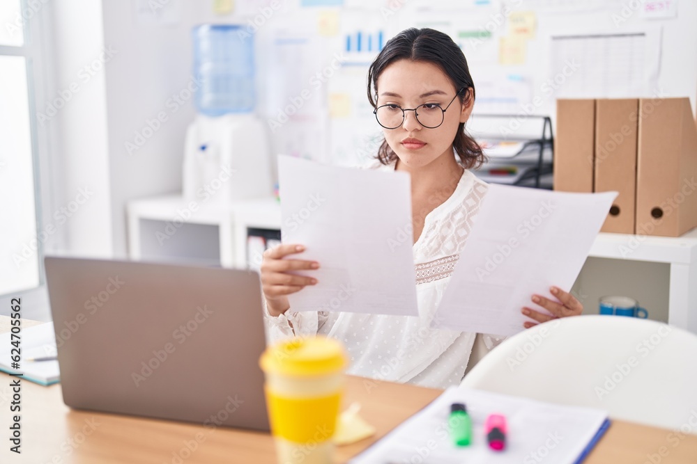 Young hispanic woman business worker using laptop reading document at office Young hispanic woman business worker using laptop reading document at office