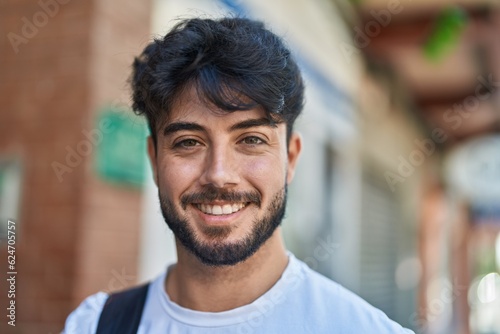 Young hispanic man smiling confident wearing backpack at street