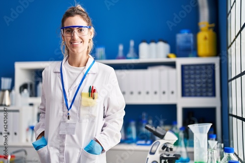 Young woman scientist smiling confident standing at laboratory