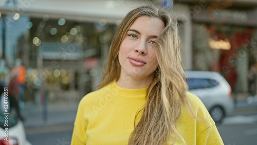 Photos Young blonde woman standing with relaxed expression at street