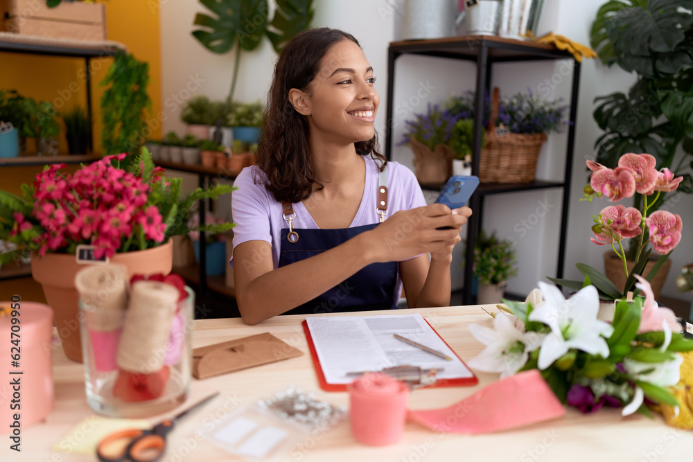 Young african american woman florist smiling confident using smartphone at flower shop