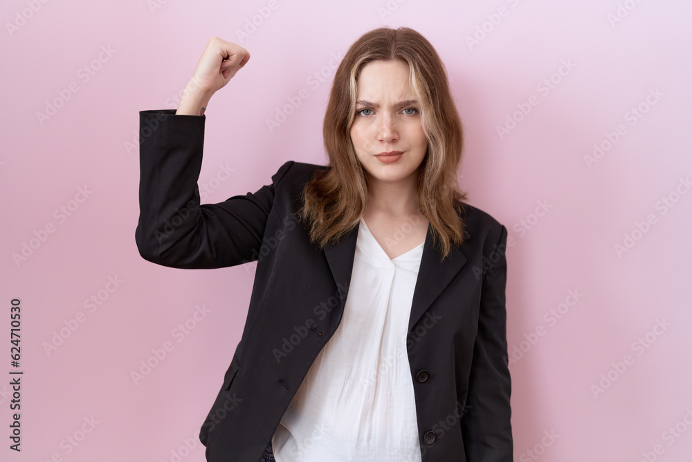 Young caucasian business woman wearing black jacket strong person showing arm muscle, confident and proud of power