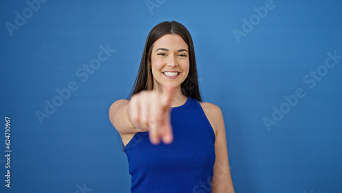 Young beautiful hispanic woman smiling confident pointing to camera over isolated blue background