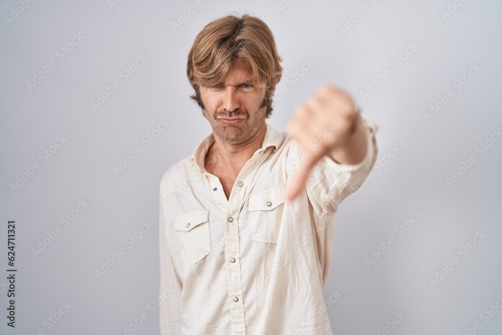 Middle age man standing over isolated background looking unhappy and angry showing rejection and negative with thumbs down gesture. bad expression. Middle age man standing over isolated background looking unhappy and angry showing rejection and negative with thumbs down gesture. bad expression.