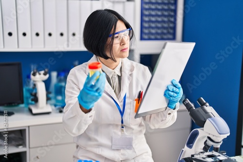 Fototapeta Naklejka Na Ścianę i Meble -  Young chinese woman scientist analysing urine reading report document at laboratory