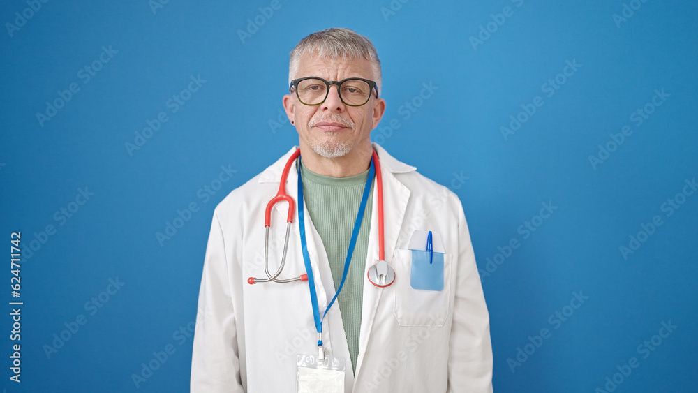 Middle age grey-haired man doctor standing with relaxed expression over isolated blue background Middle age grey-haired man doctor standing with relaxed expression over isolated blue background