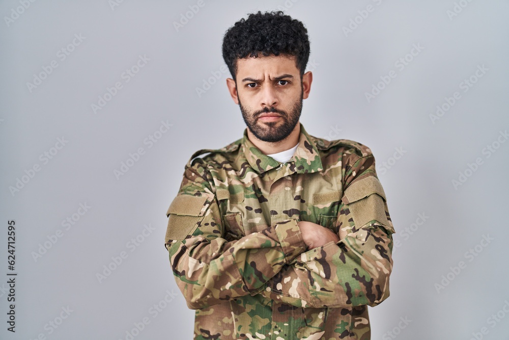 Arab man wearing camouflage army uniform skeptic and nervous, disapproving expression on face with crossed arms. negative person.