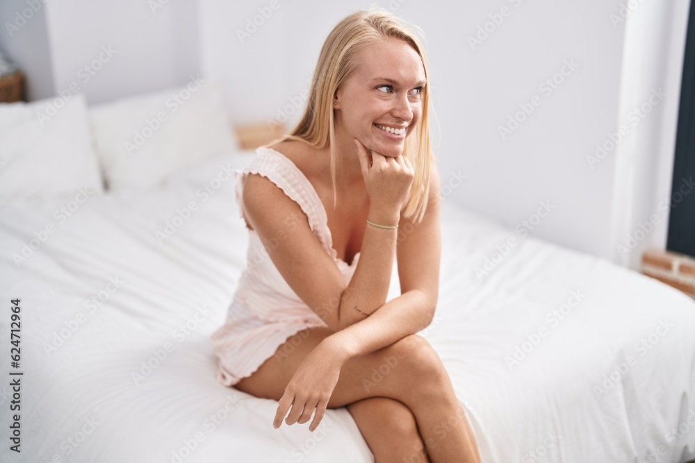 Young blonde woman smiling confident sitting on bed at bedroom Young blonde woman smiling confident sitting on bed at bedroom