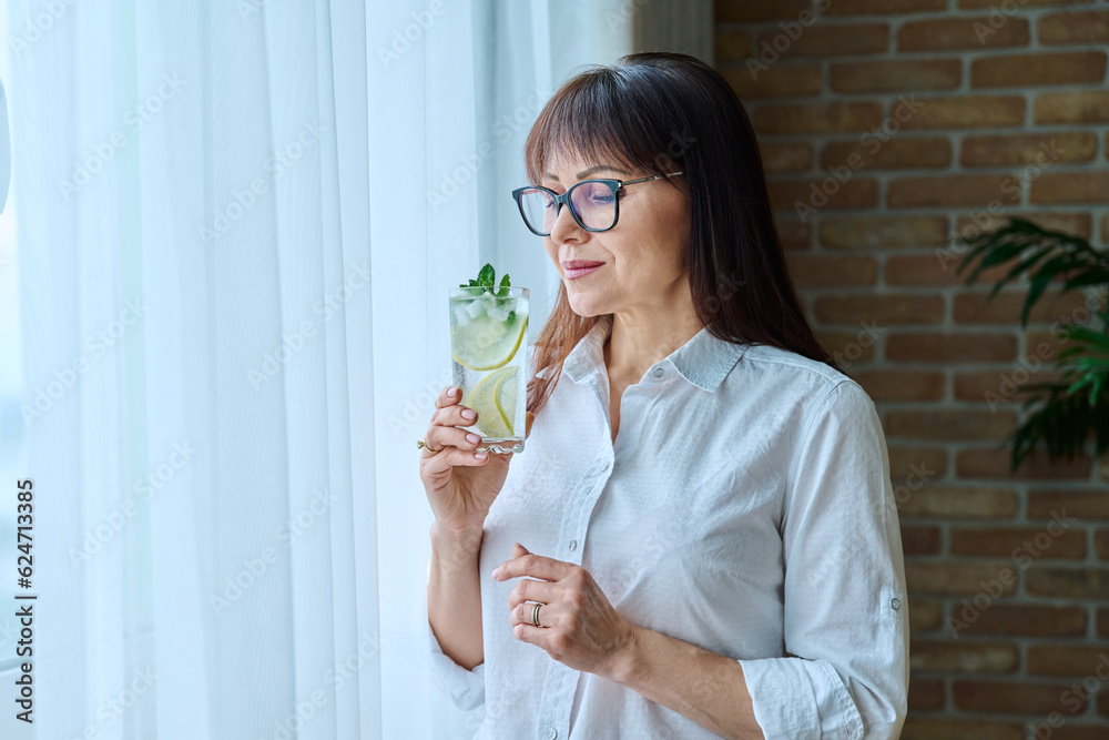 Mature woman with drink, mineral water with lemon mint ice