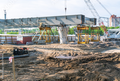 Installation of steel structures on supports during the construction of a road interchange. Road construction. Construction site with construction machinery and equipment.