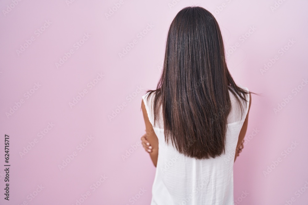 Brunette young woman standing over pink background wearing glasses standing backwards looking away with crossed arms Brunette young woman standing over pink background wearing glasses standing backwards looking away with crossed arms