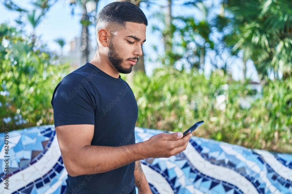 Young latin man using smartphone with serious expression at park Young latin man using smartphone with serious expression at park