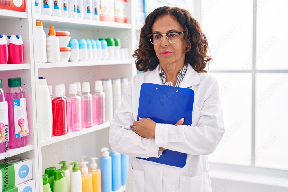 Middle age woman pharmacist holding clipboard at pharmacy