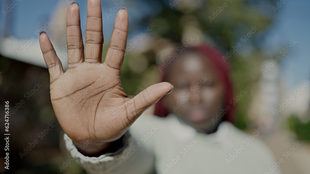 African woman with braided hair doing stop gesture with hand at street