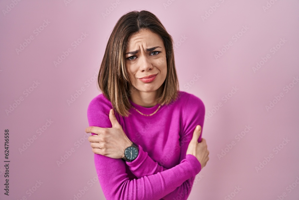 Hispanic woman standing over pink background shaking and freezing for winter cold with sad and shock expression on face Hispanic woman standing over pink background shaking and freezing for winter cold with sad and shock expression on face