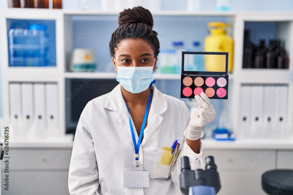 Young african american with braids working at scientist laboratory doing make up looking positive and happy standing and smiling with a confident smile showing teeth