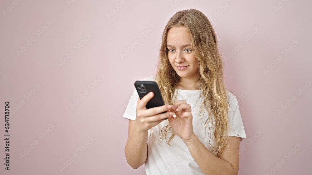 Young blonde woman using smartphone smiling over isolated pink background Young blonde woman using smartphone smiling over isolated pink background