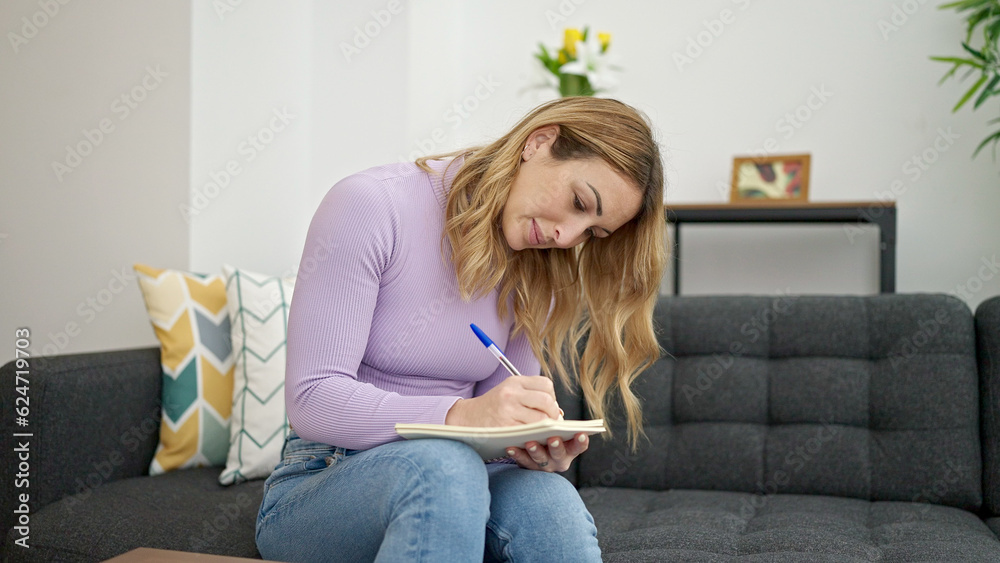 Young beautiful hispanic woman writing on notebook sitting on sofa thinking at home Young beautiful hispanic woman writing on notebook sitting on sofa thinking at home